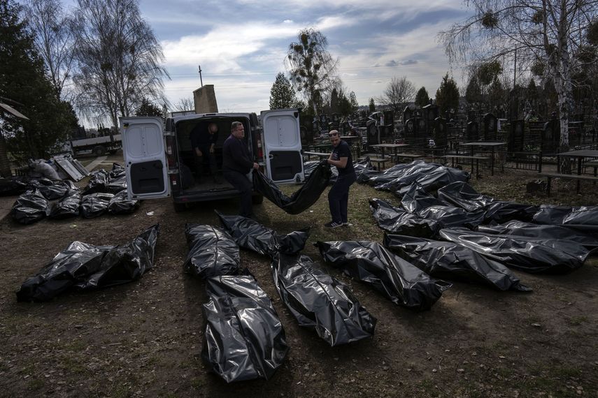 Trabajadores bajan cuerpos de civiles muertos de una camioneta en el cementerio de Bucha, en las afueras de Kiev, Ucrania, el jueves 7 de abril de 2022.