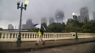 Un individuo camina bajo la lluvia con la silueta de Houston de fondo el 22 de septiembre del 2020.&nbsp;