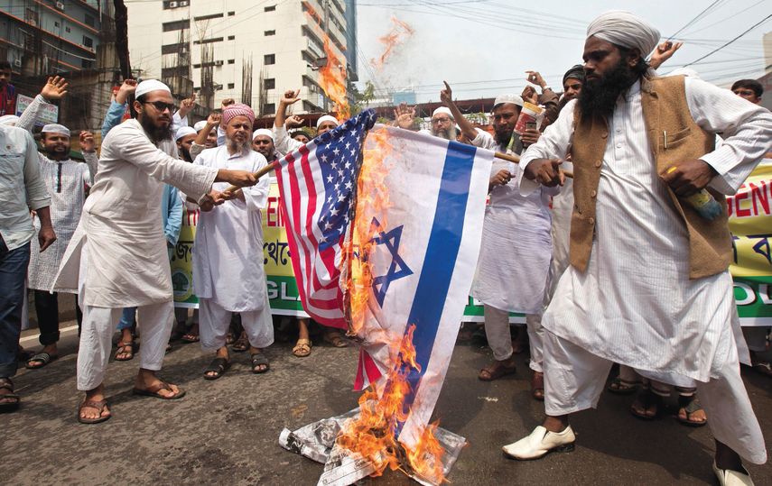 Miembros del califato islámico Andolon corean lemas mientras queman una bandera de Estados Unidos y otra de Israel durante una manifestación.