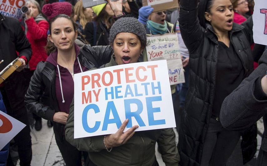 Varias personas manifiestan en EEUU con pancartas en las que se puede leer Protege a nuestra seguridad de salud.