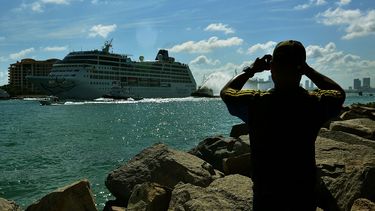 Un hombre toma una fotografía al crucero Adonia, de la compañía Fathom, filial de Carnival, a su salida del puerto de Miami.
