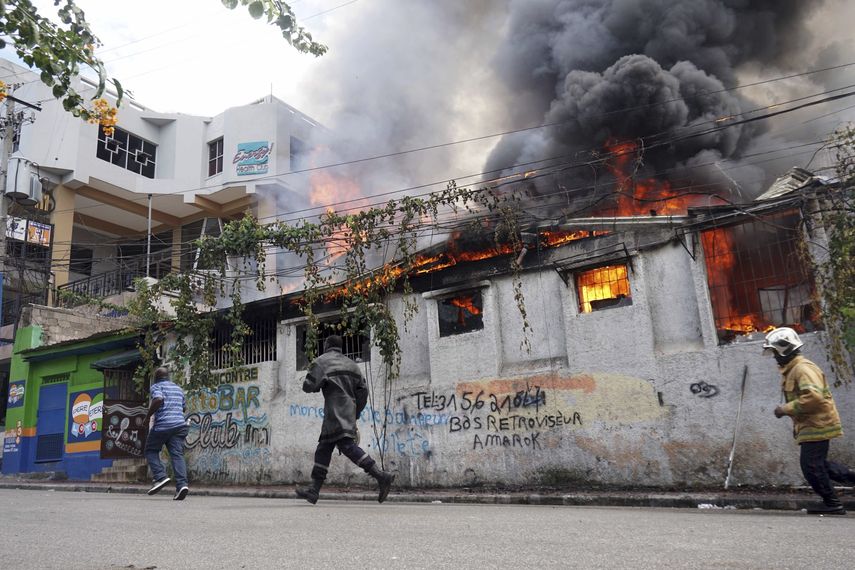Bomberos corren a un restaurante que fue incendiado durante una protesta para exigir la renuncia del presidente Jovenel Mo&iuml;se en Puerto Pr&iacute;ncipe, el viernes 27 de septiembre de 2019.&nbsp;