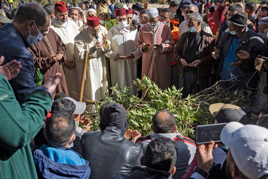 Marroquíes rezan sobre la tumba de Rayan Oram, de cinco años, en el pueblo de Ighrane, en la provincia rural de Chefchaouen, en el norte de Marruecos, el 7 de febrero de 2022. Los marroquíes asistieron hoy al funeral del niño que pasó cinco días atrapado en un pozo, provocando una vasta operación de rescate que se apoderó del mundo pero terminó en tragedia.