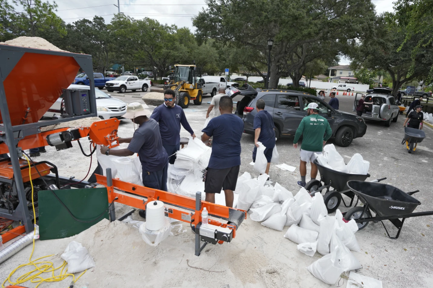Funcionarios del Departamento de Parques y Recreación de Tampa, Florida, entregan costales de arena a los residentes, el lunes 28 de agosto de 2023, en Tampa. 