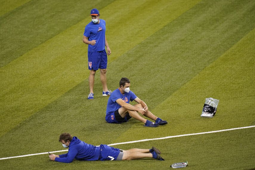 Jugadores de los Mets de Nueva York sentados en el campo antes del juego ante los Marlins de Miami
