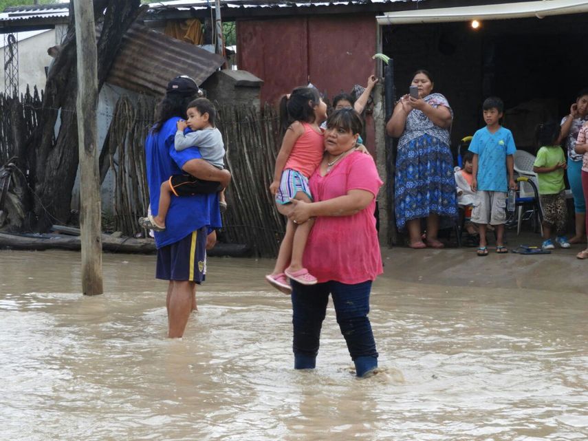 Un grupo de personas permanece en una calle inundada en la provincia de Salta (Argentina).
