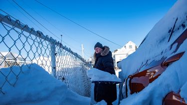 Una mujer trata de limpiar la nieve para poder sacar su auto dentro de la nieve en Massachusetts.