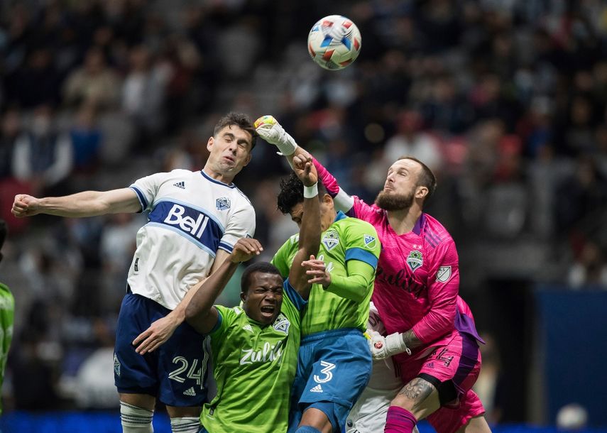 Stefan Frei, derecha, portero de Sounders de Seattle, despeja con el puño el balón ante el intento de remate de Brian White, izquierda, de Whitecaps de Vancouver, durante la primera mitad del juego de la MLS el domingo 7 de noviembre de 2021, en Vancouver
