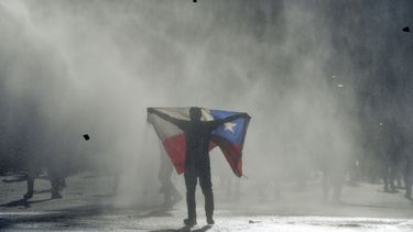 ARCHIVO - En esta imagen de archivo del 25 de octubre de 2019, un manifestante contrario al gobierno sostiene una bandera chilena en choques con la polic&iacute;a en Valpara&iacute;so, Chile.&nbsp;
