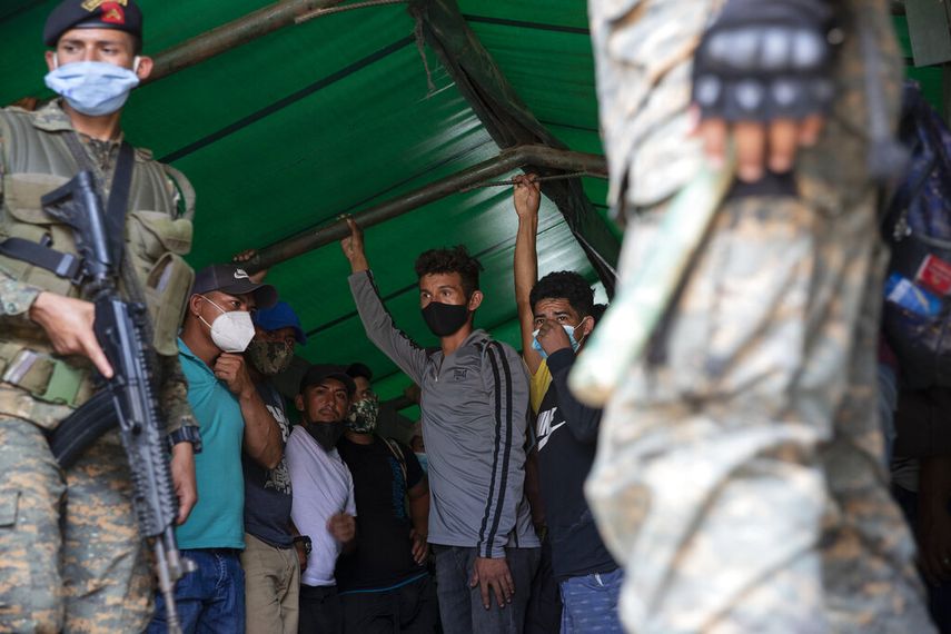 Migrantes hondureños de pie en un vehículo del ejército guatemalteco antes de regresar a su hogar, el sábado 3 de octubre de 2020, en Morales, Guatemala
