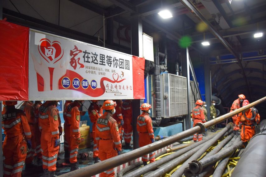 En esta imagen publicada por la agenica de noticias Xinhua, trabajadores de rescate junto a un cartel que dice El hogar es servir a tu región a la entrada de una mina de carbón inundada, en el condado de Hutubi, en la Prefectura Autónoma Hui de Changji, en el noroeste de la Región Autónoma Uigur de Xinjiang, China, el domingo 11 de abril de 2021. Varios mineros quedaron atrapados el sábado por una inundación subterránea, según medios.