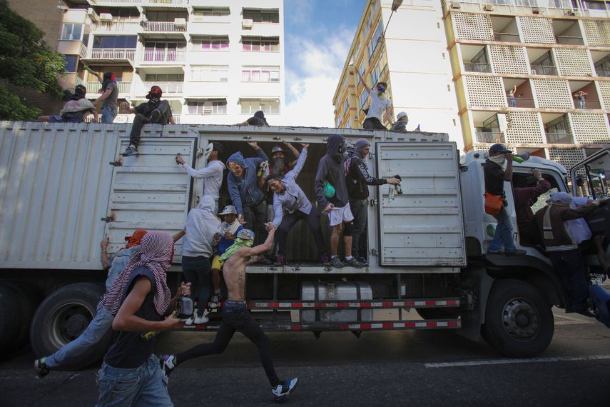 Manifestantes enmascarados protestan en contra del dictador Nicolás Maduro.
