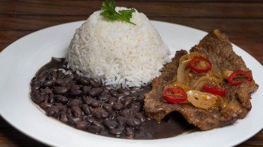 Un plato con frijoles negros, arroz blanco y carne.&nbsp;
