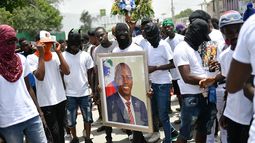 Miembros de una pandilla encabezada por Jimmy Cherizier, alias Berbecue, un expolicía que encabeza una coalición de pandillas llamada Familia G9 y Aliados, transportan un retrato del asesinado presidente Jovenel MoÍse durante una marcha efectuada el lunes 26 de julio de 2021 en el vecindario de La Saline en Puerto Príncipe, Haití, para exigir justicia tras el magnicidio