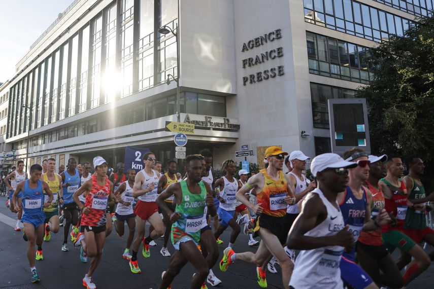 Atletas pasan por la sede de la Agence France Presse (AFP), en el maratón masculino de la prueba de atletismo de los Juegos Olímpicos de París 2024, en París, el 10 de agosto de 2024.