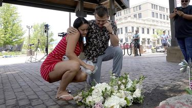 Brooke y Matt Strauss, que se casaron el domingo, hacen una pausa el martes 5 de julio de 2022 después de dejar sus ramos de boda en el centro de Highland Park, Illinois, un suburbio de Chicago, cerca de la escena de la masacre del lunes.&nbsp;