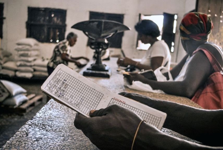 Unas personas esperan comida en una tienda, mientras una de ellas sostiene una libreta, una tarjeta de racionamiento que desde 1963 permite a los cubanos comprar alimentos básicos.&nbsp;