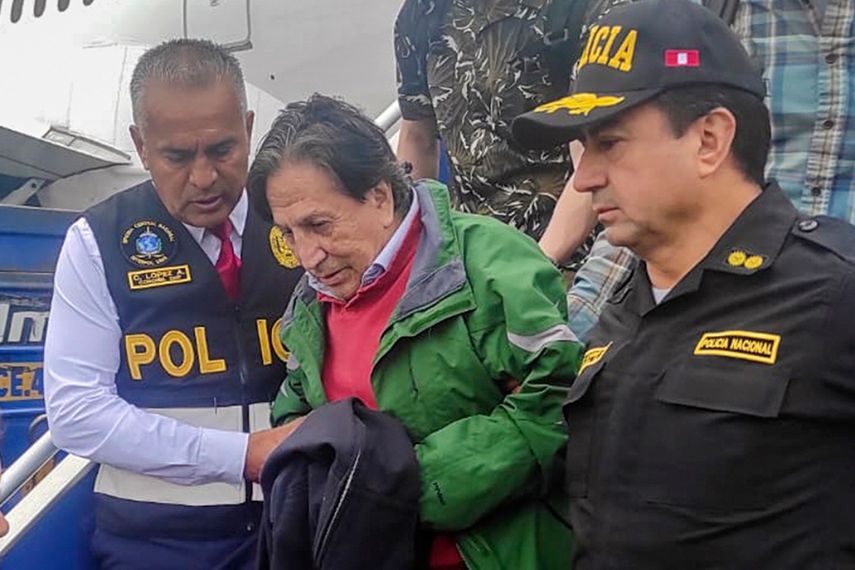 En esta foto difundida por la Policía Nacional de Perú, agentes escoltan al expresidente Alejandro Toledo a su llegada, extraditado desde Estados Unidos, al aeropuerto de Lima.