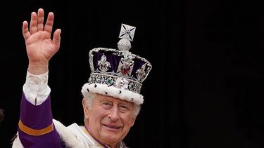 El rey Carlos III de Gran Bretaña, con la corona del estado imperial, saluda desde el balcón del Palacio de Buckingham después de ver el vuelo de la Royal Air Force en el centro de Londres el 6 de mayo de 2023, después de su coronación.