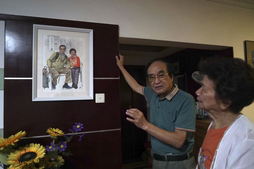 Zeng Fanzhi, un arquitecto jubilado convertido en artista, habla sobre una pintura de él con su esposa, Zhao Sirong, quien está de pie junto a él en su apartamento en Shenzhen en la provincia sureña de Guangdong en China el 27 de octubre de 2023.