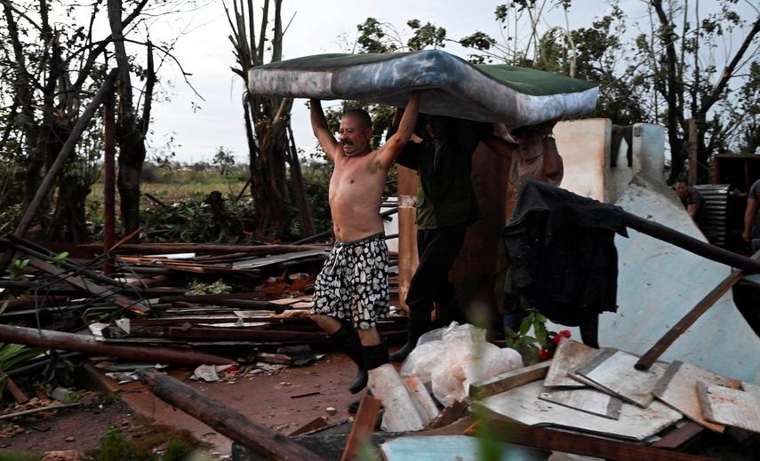 Varios hombres cargan un colchón dañado después del paso del huracán Rafael en Alquízar, provincia de Artemisa, Cuba, el 7 de noviembre de 2024.