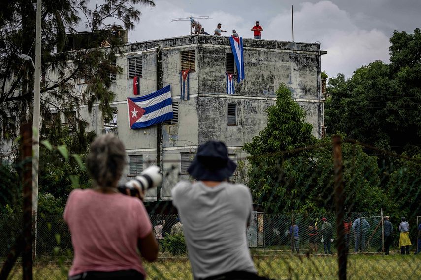 Hombres cuelgan banderas cubanas en las ventanas de la casa del activista opositor Yunior García Aguilera en un intento por evitar que se comunique con el exterior en La Habana, Cuba, el domingo 14 de noviembre de 2021.&nbsp;