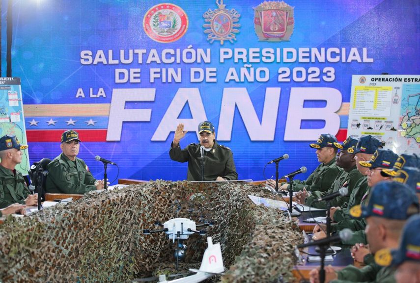 Esta fotografía publicada por la Presidencia venezolana muestra al dictador Nicolás Maduro (centro), pronunciando un discurso junto al ministro de Defensa venezolano, Vladimir Padrino López (izq.), durante una reunión con miembros de la Fuerza Armada Nacional Bolivariana (FANB) en Caracas, el 28 de diciembre de 2023.