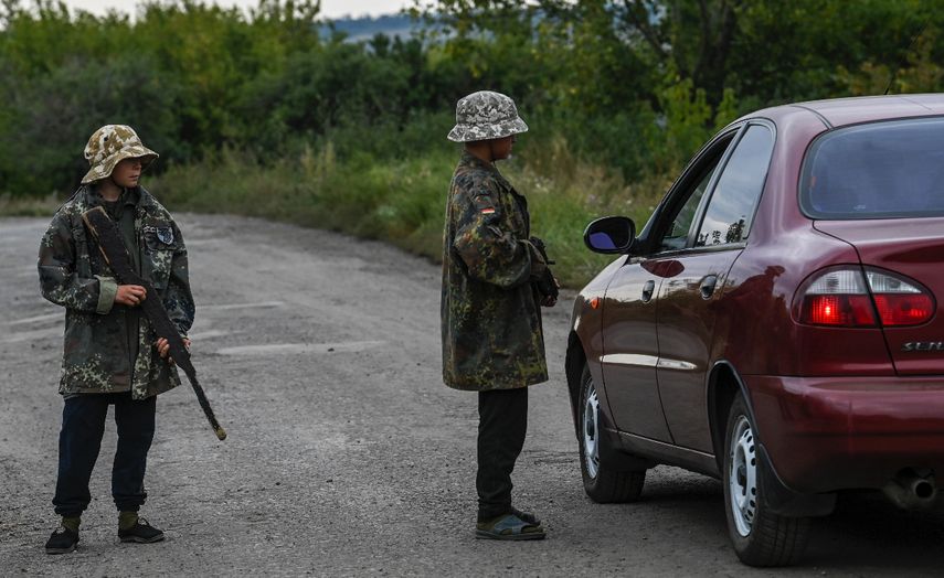 Niños ucranianos con rifles simulados de madera y plástico ocupan un puesto de control improvisado en la región de Donetsk en Ucrania, el 8 de septiembre de 2022