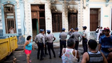 Oficiales de policía y vecinos se paran frente a una casa donde una familia de siete personas pereció en un presunto incendio en un ciclomotor eléctrico, en La Habana el 28 de junio de 2023.