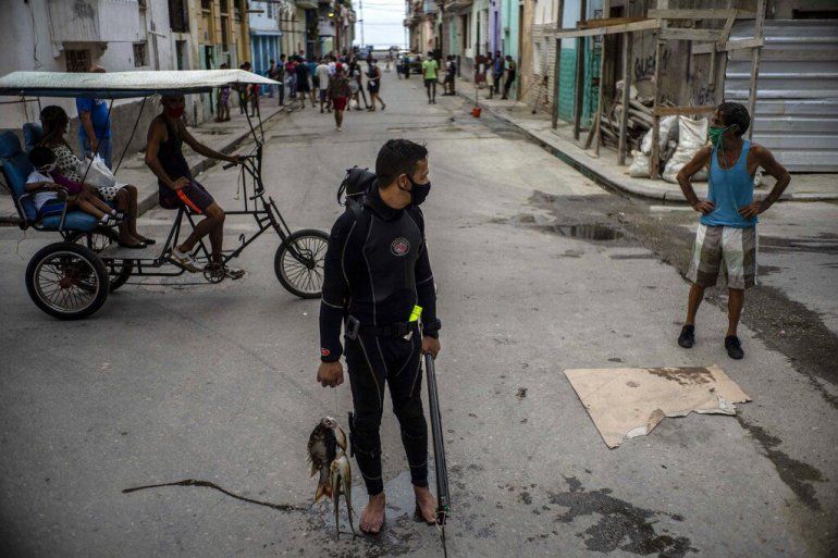 Con una mscara facial en medio de la pandemia del nuevo coronavirus, el buzo Yuniel Gonzlez camina a casa con su pesca del da en La Habana, Cuba, el martes 27 de octubre de 2020.