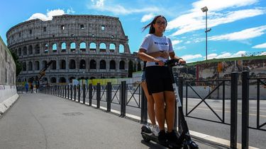 J&oacute;venes en una patineta el&eacute;ctrica cerca del Coliseo de Roma, el 22 de junio de 2020.