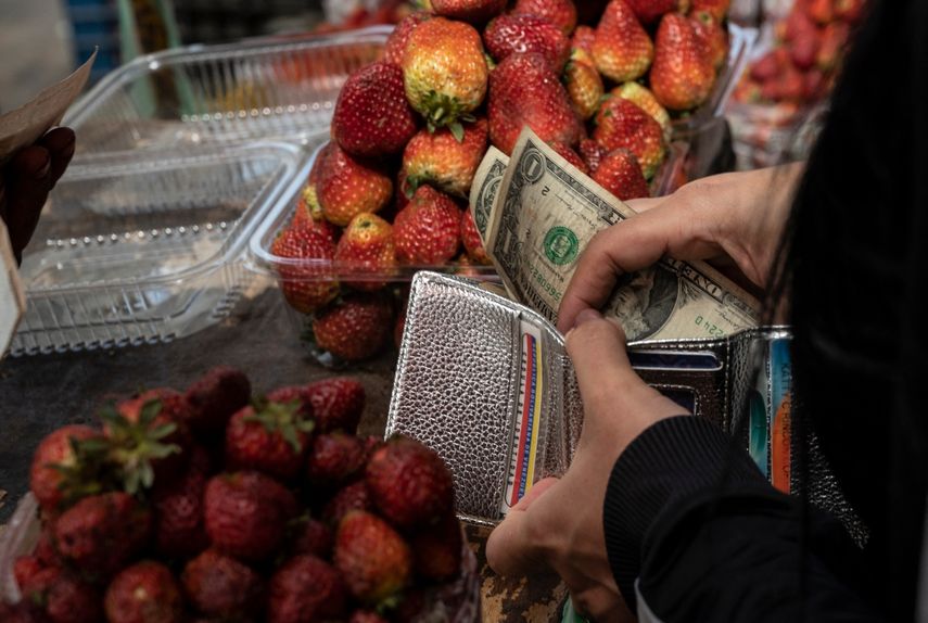 Una mujer guarda su cambio en billetes de un dólar después de comprar fruta en un puesto del mercado municipal de Quinta Crespo en Caracas.