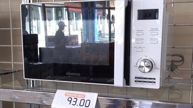 Un cliente reflejado en la puerta de un horno microondas en la tienda La Isla, de Mayar&iacute;, Holgu&iacute;n.