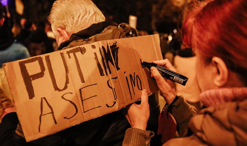 Una mujer escribe un letrero, durante una protesta en Madrid contra la invasión rusa de Vladimir Putin a Ucrania, 2022.