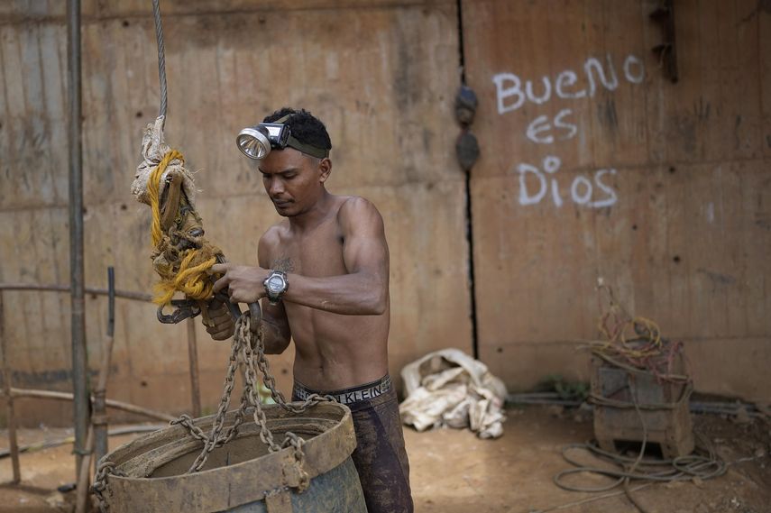 Un trabajador sujeta un gran cubo a un sistema de poleas para subir piedras por un pozo en una mina subterránea de oro en El Callao, estado Bolívar, en Venezuela, el viernes 28 de abril de 2023. Los cubos también son utilizados para subir y bajar herramientas en el lugar.