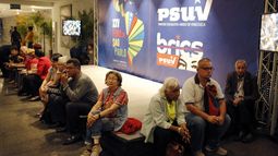 Varios participantes permanecen sentados cerca de un carteles del Foro de Sao Paulo y del Partido Socialista Unido de Venezuela durante la primera jornada de esa reunión en Venezuela, el viernes 26 de julio de 2019.&nbsp;