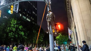 Varios manifestantes cuelgan una estatua tomada del monumento a la Confederación en el Capitolio del estado de un poste en la esquina de las calles Salisbury y Hargett en Raleigh, Carolina del Norte, la noche del viernes 19 de junio de 2020.