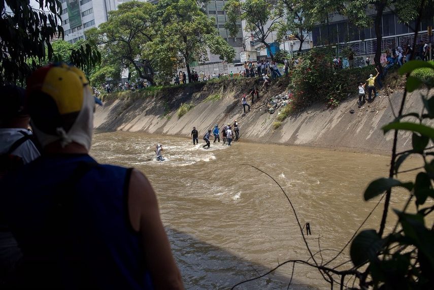 Algunos más osados han optado por cruzar, montándose en las tuberías aéreas que cruzan el Guaire de lado a lado, sostenidos de los hierros que soportan la estructura.
