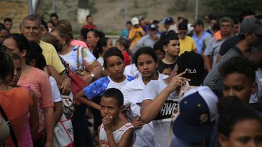 Migrantes de distintos países, incluyendo Honduras, Cuba, Venezuela y Nicaragua, hacen fila para recibir alimentos donados por voluntarios de Estados Unidos, al pie de un puente que cruza a Brownsville, Texas, en el centro de Matamoros, en el estado de Tamaulipas, México.&nbsp;