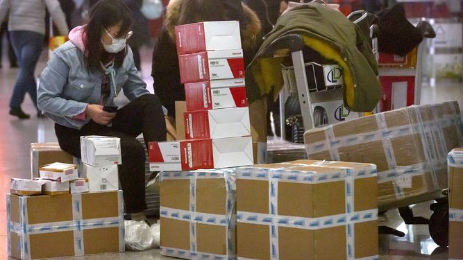 Una viajera sentada junto a cajas de mascarillas para la cara y respiradores en el aeropuerto internacional de Beijing, el 30 de enero de 2020.&nbsp;