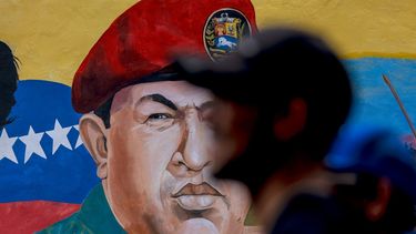 Un hombre pasa junto a un mural con la imagen del fallecido dictador de Venezuela, Hugo Chávez.