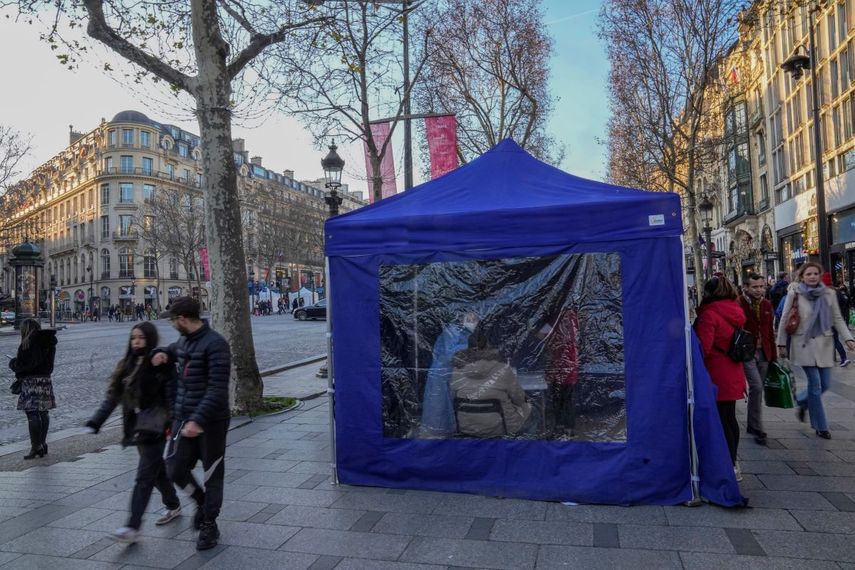 Unos médicos realizan pruebas de coronavirus en una carpa en la avenida de Campos Elíseos en París, el martes 21 de diciembre de 2021.
