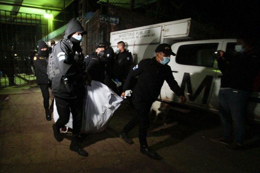 Agentes de policía transportan el cadáver de un recluso después de una pelea en la prisión de hombres de Cantel, en el departamento de Quetzaltenango, a 205 kilómetros al oeste de la ciudad de Guatemala, el 19 de mayo de 2021. Al menos seis reclusos fueron decapitados en una pelea entre bandas rivales el miércoles en una prisión. en el oeste de Guatemala, dijo la policía a la AFP.