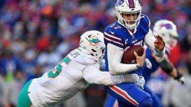 El quarterback Josh Allen (17), derecha, de los Bills de Búfalo, corre con el balón mientras el linebacker Jaelan Phillips (15), de los Dolphins de Miami, trata de derribarlo, en partido del domingo 15 de enero de 2023, en Orchard Park, Nueva York.