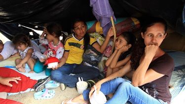 Colombianos que han retornado voluntariamente desde Venezuela permanecen con sus pocas pertenencias bajo un plástico en la Playa, sector de La Parada, Colombia. (EFE)