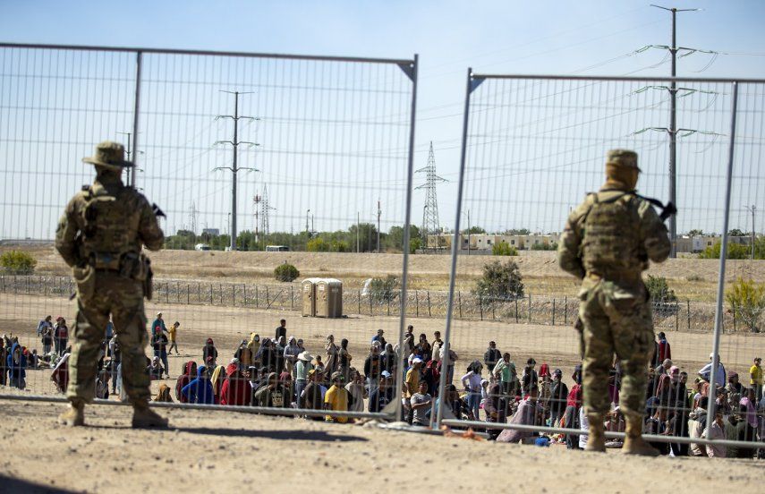 Gran cantidad de migrantes aguardan el miércoles 10 de mayo de 2023 junto a la cerca fronteriza para entrar en El Paso, Texas, ante la mirada de miembros de la Guardia Nacional del estado. 