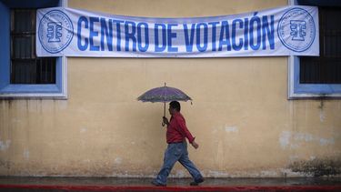 Un hombre camina bajo la lluvia rumbo a un centro de votación durante las elecciones generales en Antigua, Guatemala, el domingo 16 de junio de 2019.