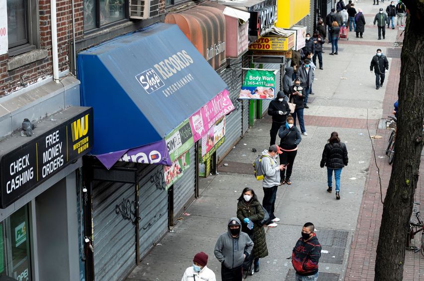 Personas usan máscaras mientras hacen cola para ingresar a una tienda que ofrece servicios de cambio de cheques, el 14 de abril de 2020 en la ciudad de Nueva York.