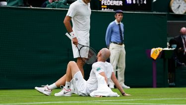 Roger Federer charla con Adrian Mannarino tras la lesión sufrida por este en el duelo de primera ronda del torneo de Wimbledon, el martes 29 de junio de 2021, en Londres