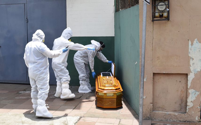 &nbsp;En esta fotograf&iacute;a de archivo del 6 de abril de 2020, trabajadores con equipo protector contra el coronavirus recogen un f&eacute;retro que contiene los restos de un cuerpo al lado de una casa en Guayaquil, Ecuador.